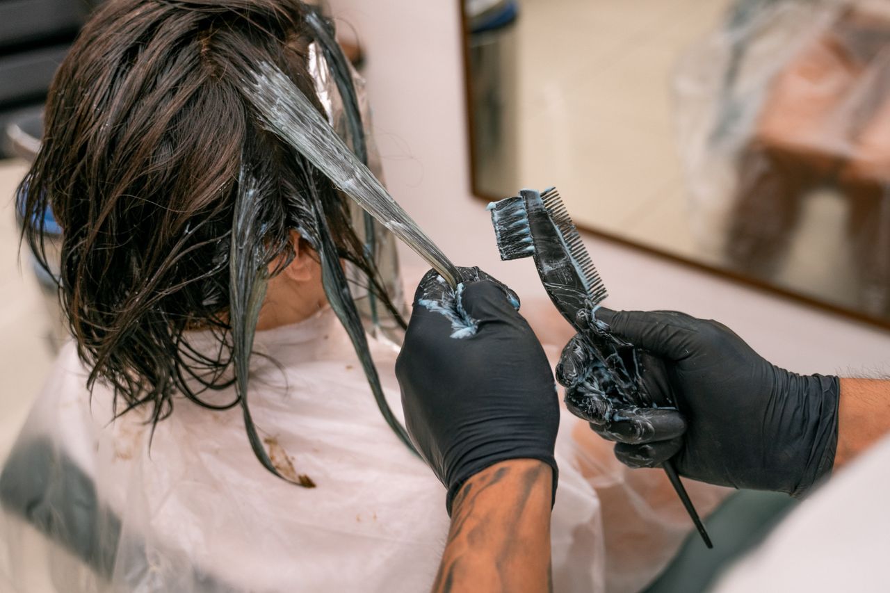 Close-up of hair coloring process in a salon. Hairdresser applying dye to client's hair.
